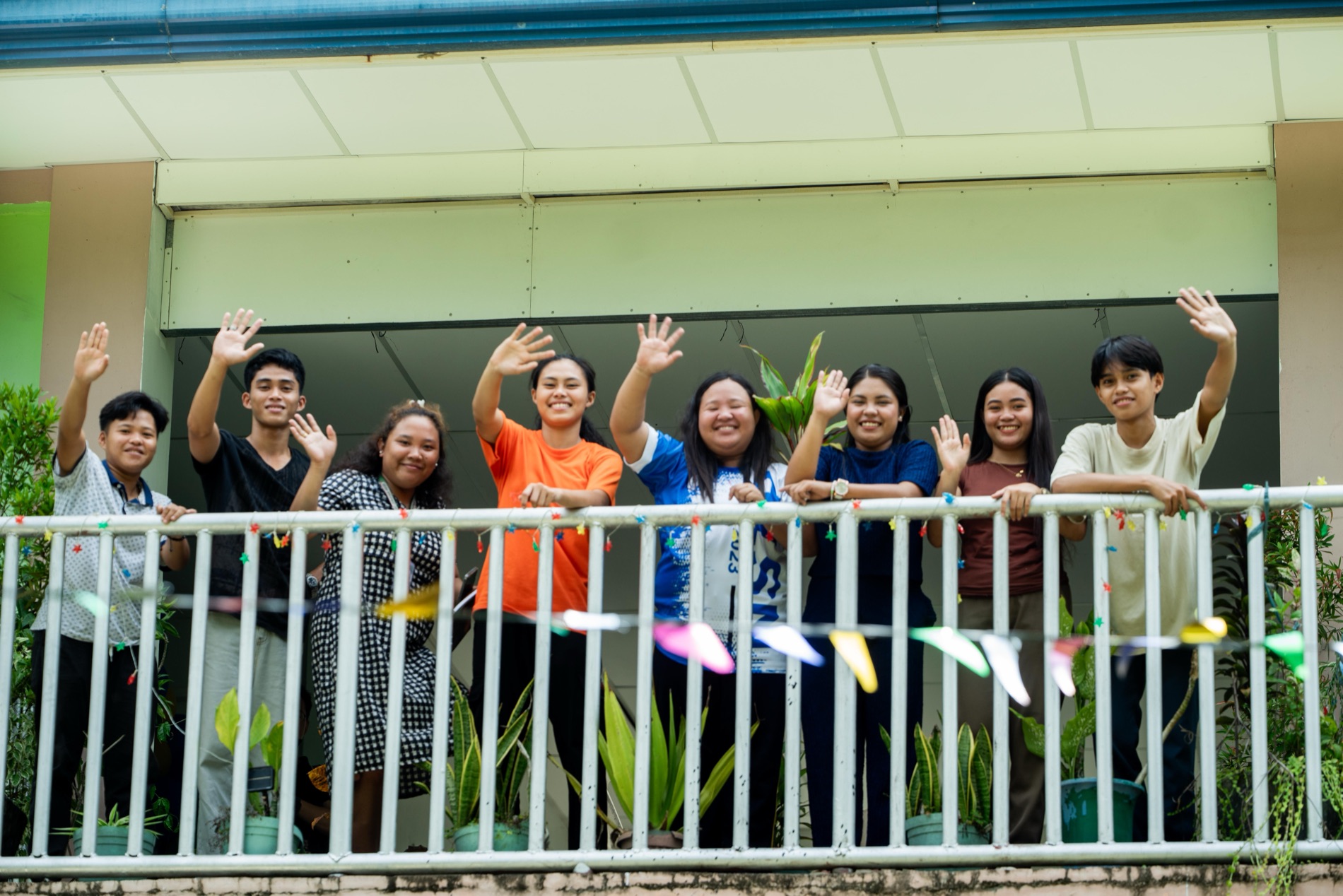 A group of young people in Mindanao smiling and waving together