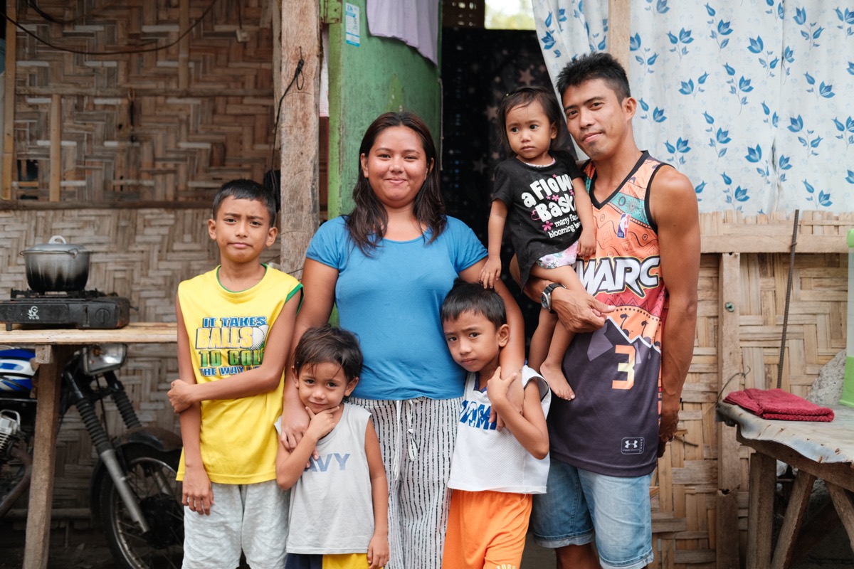 A smiling family outside their home in Mindanao