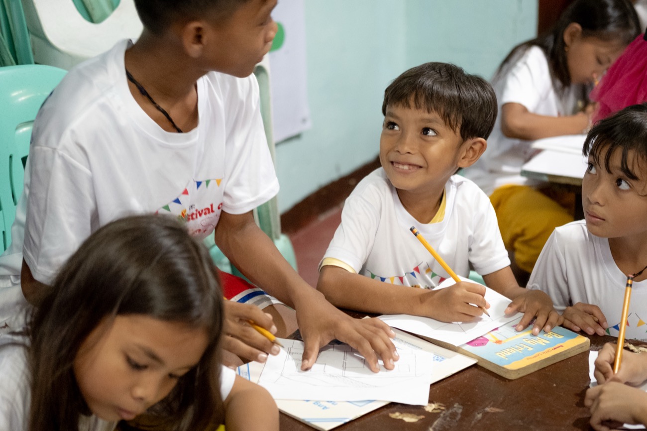 Children smiling and drawing together at a Mindanao program
