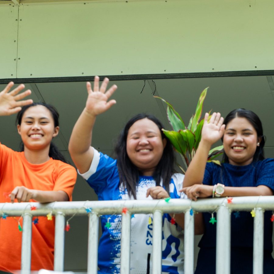 Young people waving and smiling from a balcony in Mindanao