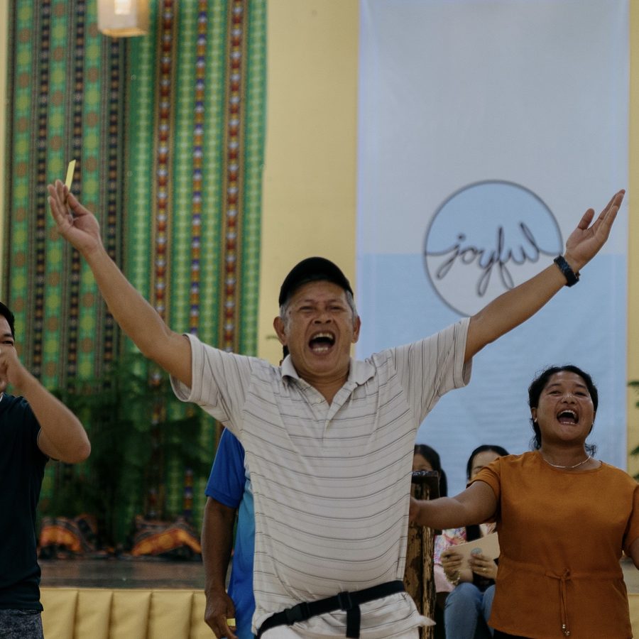 A man singing joyfully with arms open wide