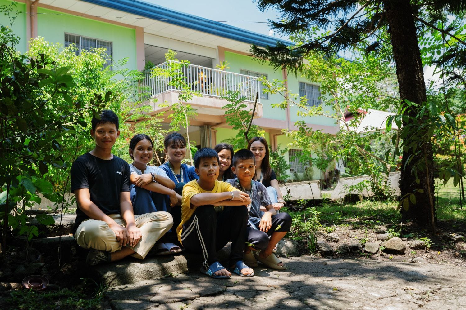 Young people from Mindanao sitting together outside a school building